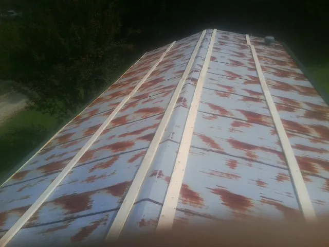 Rusted metal roof panels with new wood purlins before replacement — Storm Damage Roof Repair in Savage by Roofing Brothers