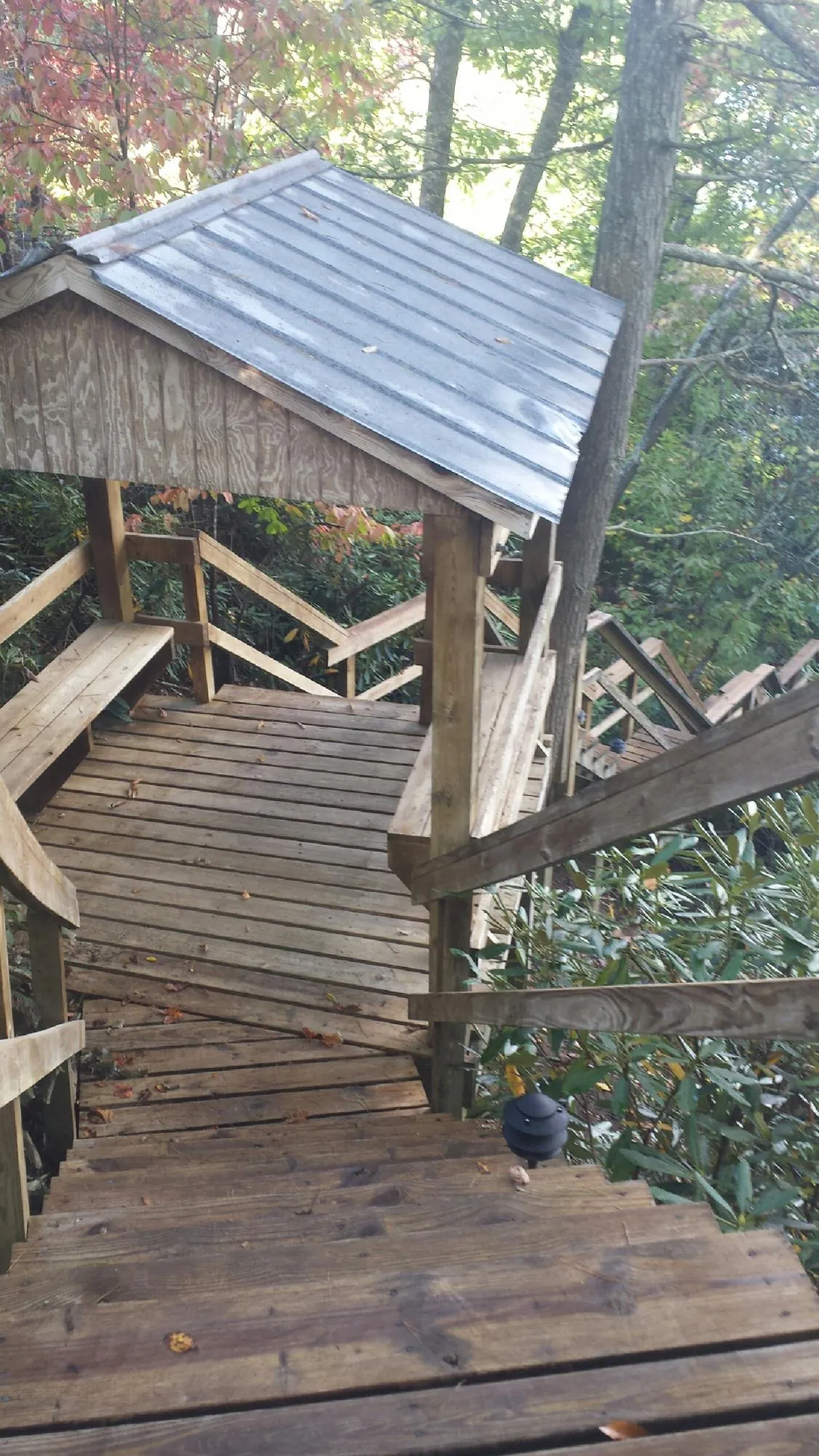 Metal roofed shelter over wooden steps on a wooded walkway — Skylight Repair & Installation work by our crew in Savage